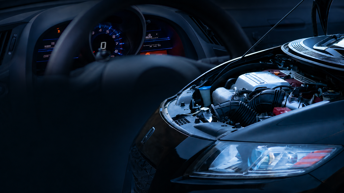 Car engine compartment with open hood in a dark setting